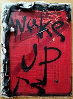 Full view of the canvas showing the red textured background with the words 'Wake Up' painted in black dripping letters, surrounded by fabric edges with black and white paint.