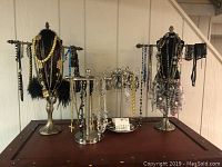 Wide shot of jewelry stands displaying multiple necklaces, bracelets and earrings in various metallic colors plus some beaded necklaces.