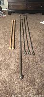 Five rods laid on carpet, including three satin nickel curtain rods with rings or balls and two wooden closet bars with rounded ends