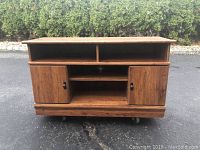 Front view of the solid wood TV stand showing two hinged doors and two open shelves above.