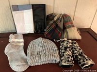 Winter scarf, gloves, socks, beanie and leather gloves in box on wooden surface.
