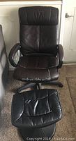 Brown faux leather office chair showing wear and peeling on seat, paired with black faux leather ottoman. Chair does not adjust height.