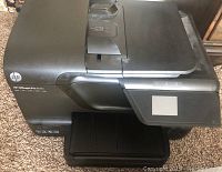 Oblique front view of the HP OfficeJet Pro 8600 showing the control panel with touchscreen and paper tray.