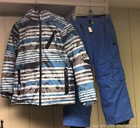 Photo of 686 youth ski snowboard winter coat and snow pants, showing striped coat and solid blue pants hanging together.