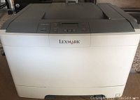 Front view of Lexmark laser printer showing brand logo, control panel, and paper tray.