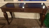 Solid wood sofa table with glass inset top shown from front view, highlighting the overall shape and finish.