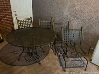 Overview of round metal patio table, umbrella base and four metal lattice chairs