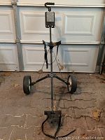 Front view of the folding golf bag pull cart showing padded handlebar, adjustable straps, and two rear wheels.