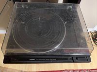 Top view of Toshiba SR-5617 turntable with closed clear plastic dust cover, showing the circular platter and control panel.