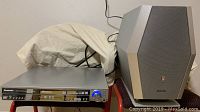 Photo showing Panasonic DVD/CD player unit with front panel controls, disc drawer closed, and subwoofer speaker beside it.