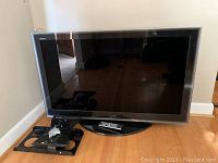 Front view of 55" Toshiba Regza HDTV on stand with remote and wall mount on floor