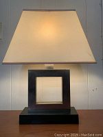 Front angle showing lamp turned on with warm light, highlighting design and lampshade condition.