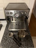 Front view of Breville espresso machine with portafilter attached and milk frothing pitcher on countertop