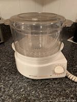 Photo of entire Black & Decker Handy Steamer showing clear plastic steaming basket on white base with dial timer.