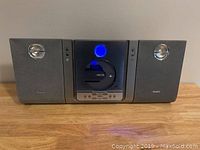 Frontal view of Philips CD player and tuner with both attached speakers, unit powered with blue light showing in CD compartment