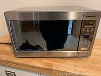 Front and closed view of Panasonic microwave with stainless steel finish and control panel.