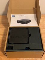 Open cardboard box showing WD TV Play media player boxed with manual on top