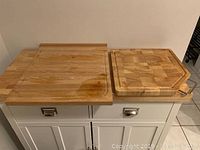 Both wooden cutting boards on a countertop, showing size difference and overall appearance