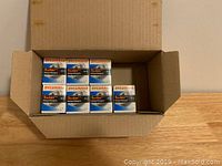 Open box showing seven individual boxes of Sylvania Tru-Aim MR16 bulbs inside placed on wooden surface.