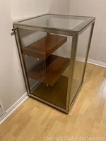 Angled front view showing stainless steel frame, glass panels, top, and cherry wood shelves