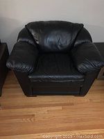 Front view of black leather armchair showing overall style and cushioning.