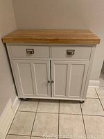 Front view of cabinet with drawers and doors closed showing butcher block top and caster wheels