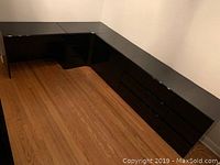 Seven-piece black lacquer bedroom furniture set arranged in a corner, showing the glossy finish and overall condition.