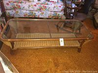 Full view of rectangular coffee table with glass top and wicker lower shelf, showing overall design and condition.