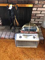 Wrought iron fireplace tool set, brass wood holder with fire logs, and Comfort Zone electric space heater, shown together in front of fireplace