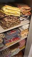 Shelf with folded bed sheets stacked in piles, various patterns and colors including florals and geometric designs