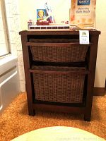 Front of wooden storage cabinet with two woven basket drawers with personal care items on top.