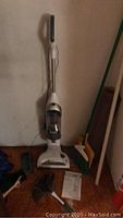 Photo showing Shark Freestyle upright vacuum cleaner, power cord, instruction manual, reusable vacuum bags and duster on floor