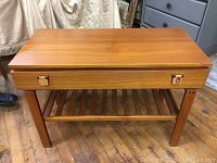 Full front view of teak side table showing top storage lid and slatted shelf below
