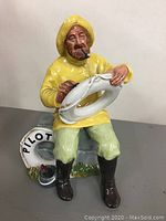 Full front view of the Royal Doulton figurine showing the man in yellow rain gear holding a white life ring marked 'PILOT' with a cigar in his mouth.