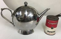 Side view showing the polished stainless steel teapot next to a Campbell's soup can for scale.
