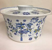 Side view of white ceramic serving bowl with lid, decorated with blue and green floral patterns and a woman figure. Shows bowl closed with lid.