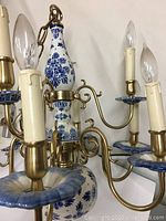 Overall chandelier showing porcelain central and base pieces, brass arms and candle lights