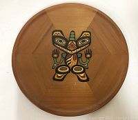 Full view of circular red cedar plate with centered Indigenous bear design in multiple colors.