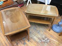 Pair of vintage mid century modern wooden side tables with glass tops and lower shelves viewed from above