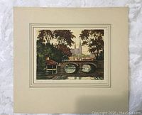 Full view of vintage watercolour painting mounted on beige board, showing bridge, trees, and cathedral in background