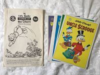 Photo showing a portion of the 20 colorful double-sided posters with classic Uncle Scrooge covers artwork, alongside the packaging.