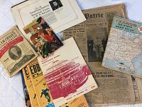Wide view of all ephemera items laid out showing various newspapers, pamphlets, catalog, and a Texaco Road Atlas.