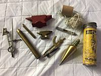 Full lot on white quilted surface showing multiple vintage miniature tools including anvils, plumb bob and more.