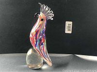 Front and side view of the Murano art glass parrot paperweight showing swirled colors and clear glass crest