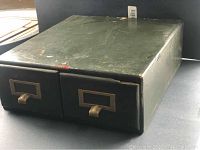 Top and front view of green-painted solid wood filing drawers with brass handles showing wear and some paint chipping.