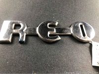 Close-up of REO emblem letters showing chrome finish and surface details
