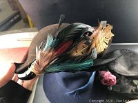 Brown wool felt hat with colorful feathers including turquoise, red and beige feathers on the side.