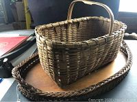 Photo showing the smaller rectangular wicker basket placed on the large wooden tray with wicker sides, highlighting the wood tray surface and the basket's handle.