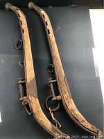 Photo showing both wooden horse hames side by side on a flat background, illustrating overall structure, length, and attached metal fittings.