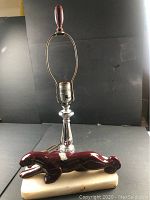 Full view of the lamp showing the ceramic red cougar on marble base with metal lamp holder and red finial.
